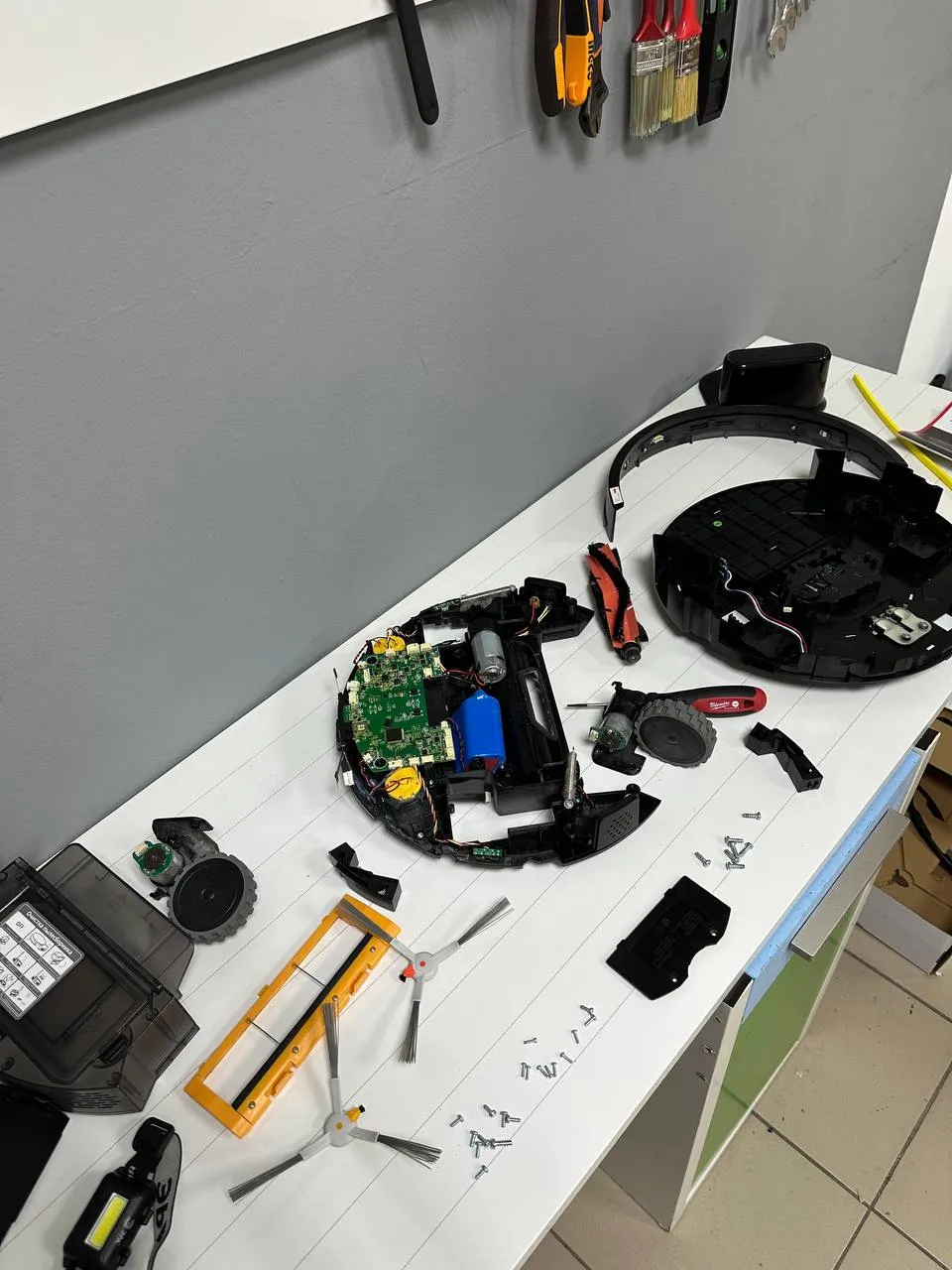 Разобранный робот-пылесос Okami U100 Plus на рабочем столе.